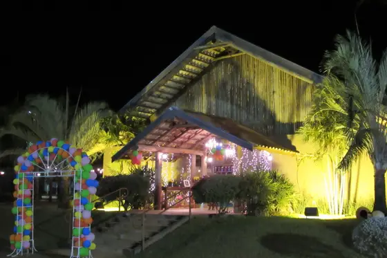 Fachada iluminada à noite com arco de balões na entrada