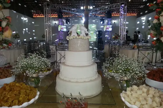 Bolo de casamento de quatro andares cercado por arranjos de flores