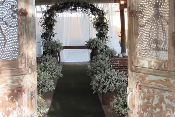 Arco de folhagem e flores brancas na entrada do salão