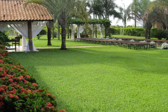 Quiosque de telhado de barro no gramado com canteiros floridos