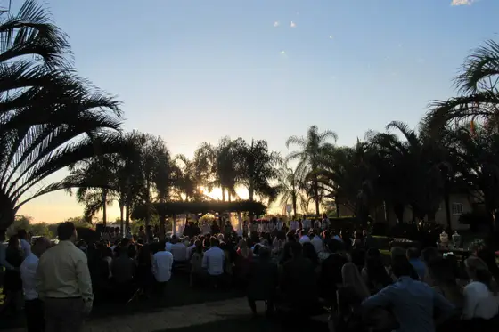 Cerimônia ao ar livre ao pôr do sol com convidados sentados