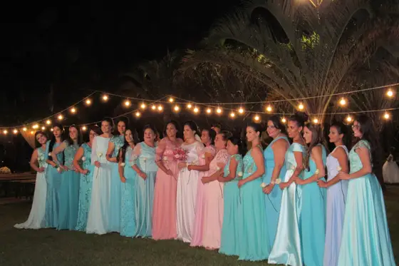 Convidadas em vestido longo sob varal de luzes à noite