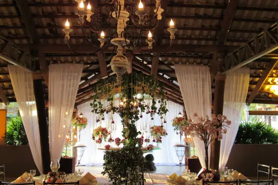 Salão com lustres, cortinas e arranjos suspensos de flores