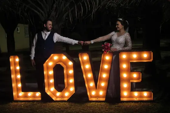 Casal diante do letreiro iluminado “LOVE” à noite