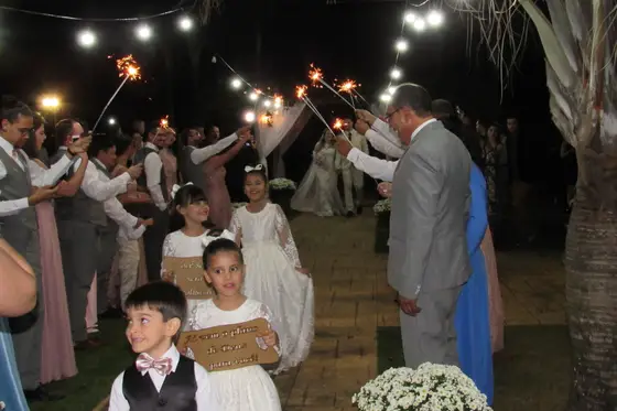 Convidados formando corredor com velas faíscas na saída dos noivos
