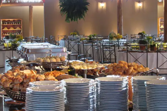 Buffet montado com travessas quentes e pilhas de pratos
