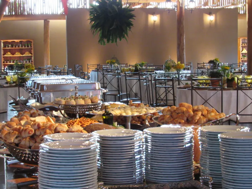 Buffet montado com travessas quentes e pilhas de pratos
