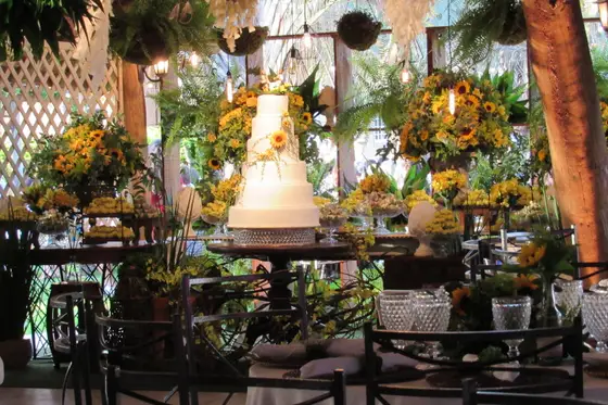 Mesa de bolo com arranjos de flores e frutas