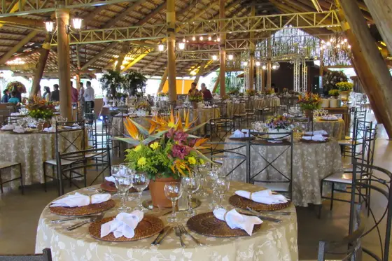 Mesa posta com arranjo alto de flores, louça e taças