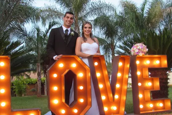 Casal de noivos diante do letreiro iluminado “LOVE”