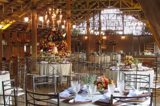 Salão decorado com mesas redondas e arranjos de flores