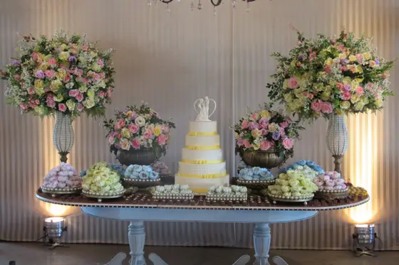 Mesa de bolo com arranjos de flores em tons de rosa