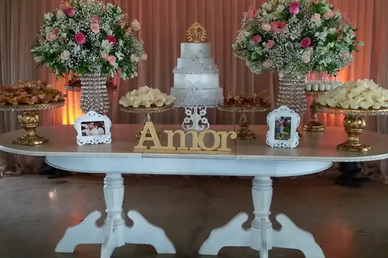 Mesa de bolo com letreiro “Amor” e arranjos de flores brancas
