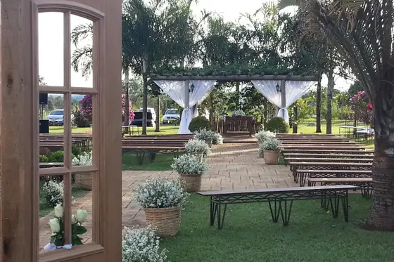 Área externa com bancos de madeira sob pergolado e gramado ao fundo