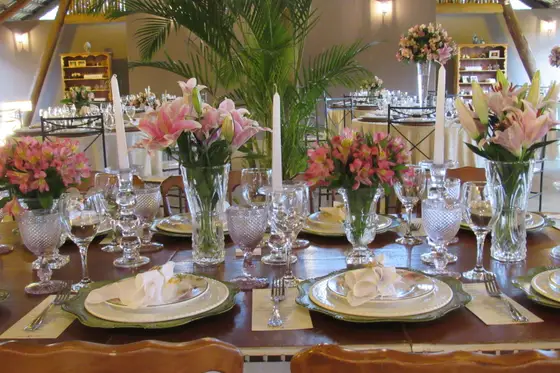 Mesa posta com arranjo de flores, taças de cristal e velas