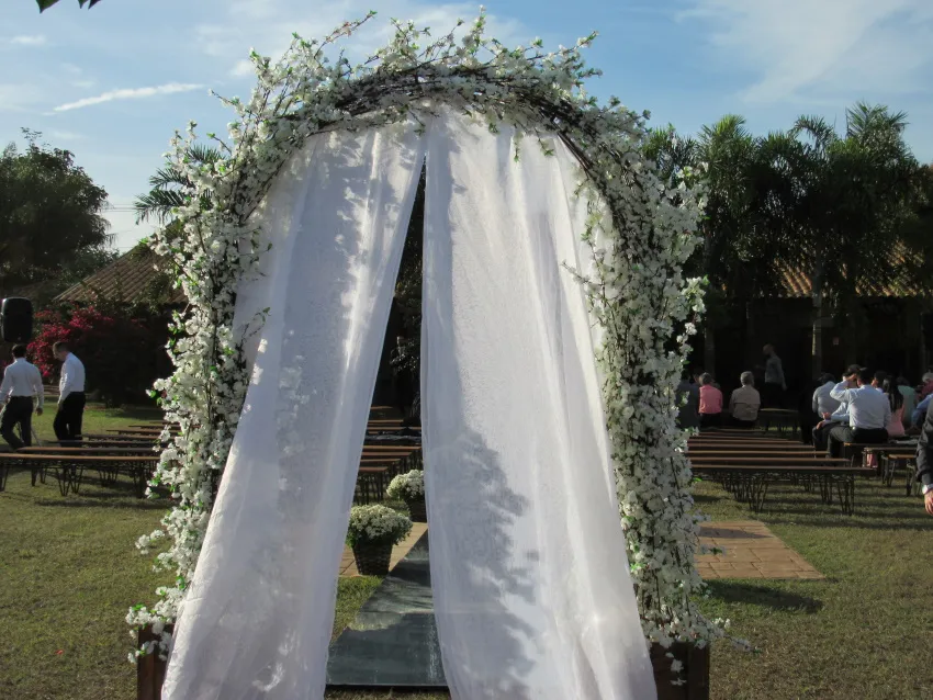 Arco de flores brancas com cortinas montado no gramado
