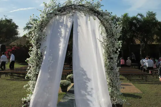 Arco de flores brancas com cortinas montado no gramado